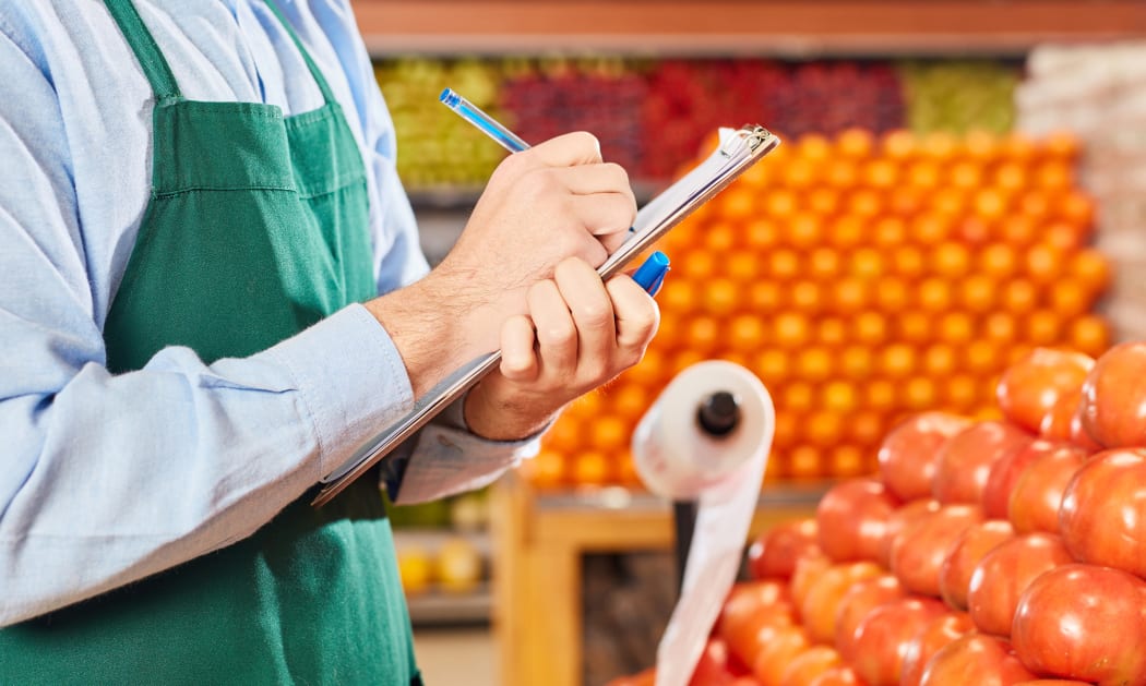 Businessman in the supermarket at inventory with checklist in the vegetable department