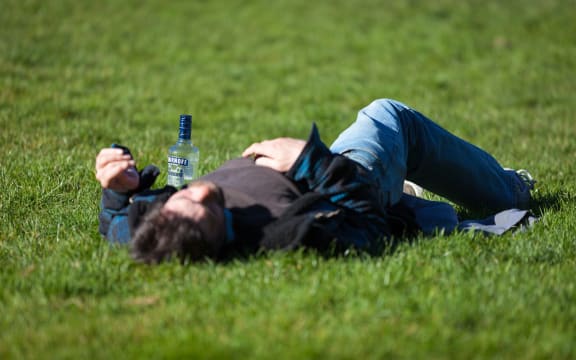 man lying in field with vodka bottle