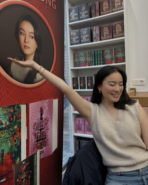 Chloe Gong, in France, puts up her hand to a picture of herself in a bookshop.