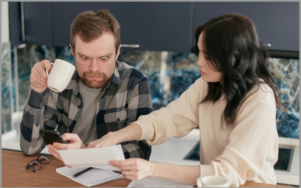 Image of man shocked at bill by wife.