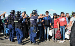 Police move refugees away from a road at the refugee camp in Roeszke, Hungary,