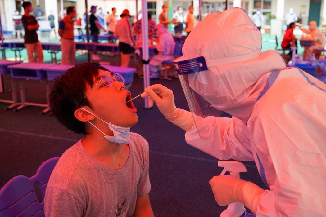 A medical worker takes a swab sample from a citizen at a Covid-19 nucleic acid testing site in Guangling District of Yangzhou, east China's Jiangsu Province, Aug. 11, 2021.