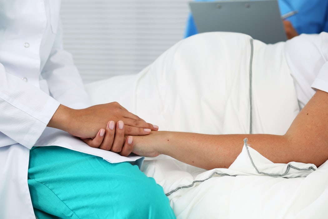 medical professional holding pregant woman's hand