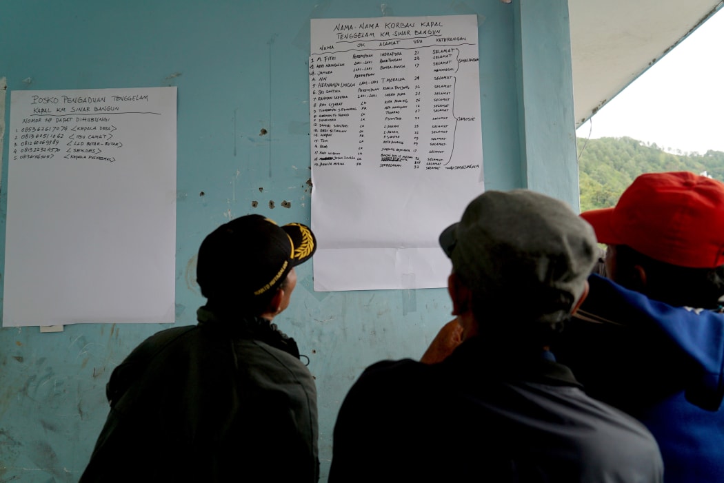 Family members look at a survivor list at the Lake Toba ferry port in the province of North Sumatra on June 19, 2018, after a boat capsized on June 18.