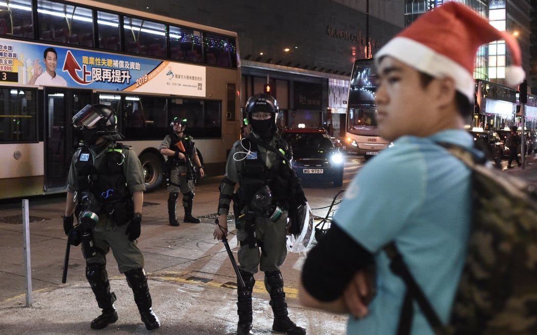A man with a Santa hat stands in front of riot police during a protest in Mong Kok district in Hong Kong on Christmas day - December 25, 2019.