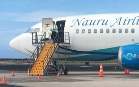 A Nauru Airlines pilot, donned in Covid-19 prevention gear, waits for local officials to collect flight manifest documents. No passengers or crew deplaned from Friday's flight to Majuro, which took about 10 passengers out of Majuro.