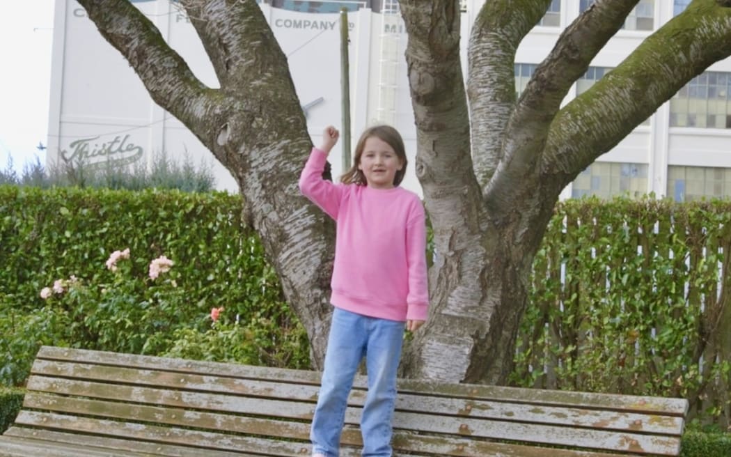 A young girl signals to the drivers to honk their horns.
