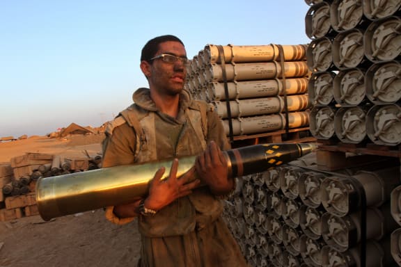 An Israeli soldier carries a shell as troops prepare ammunitions along the border with the Hamas-controlled Gaza Strip.