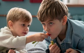 Two boys sharing a carrot