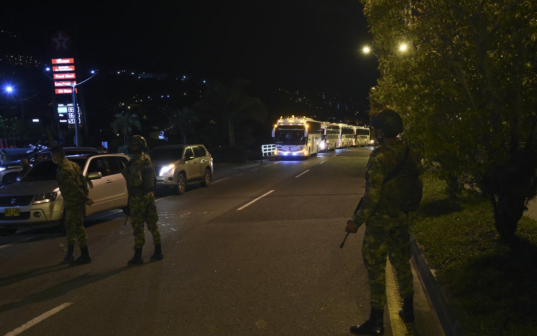 Colombians soldiers stand guard as the caravan carrying former FARC guerillas stopped at a gas station while heading to Mutata, Antioquia department, Colombia, on July 16, 2020 after being evacuated from the Territorial Area of Training and Reincorporation (ETCR) of Santa Lucia near Ituango. More than 90 ex-FARC guerrillas and their relatives were transferred from the Santa Lucia ETCR to Mutata, following a series of deadly attacks which killed 11 demobilized FARC rebels after the signing of the peace treaty between the FARC and the Colombian Government in 2016. (Photo by JOAQUIN SARMIENTO / AFP)