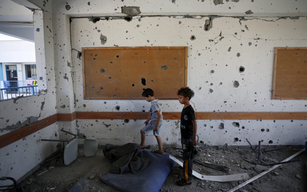 Young boys stand in a shrapnel-pocked room inside a UN-run school in the refugee camp of Al-Maghazi in the central Gaza Strip, a day after at least 6 people were killed in a reported Israeli strike, on October 18, 2023. Dozens of people, including UNRWA staff, were wounded and the school suffered severe structural damage, the United Nations agency for Palestinian refugees said. (Photo by Mohammed Faiq / AFP)