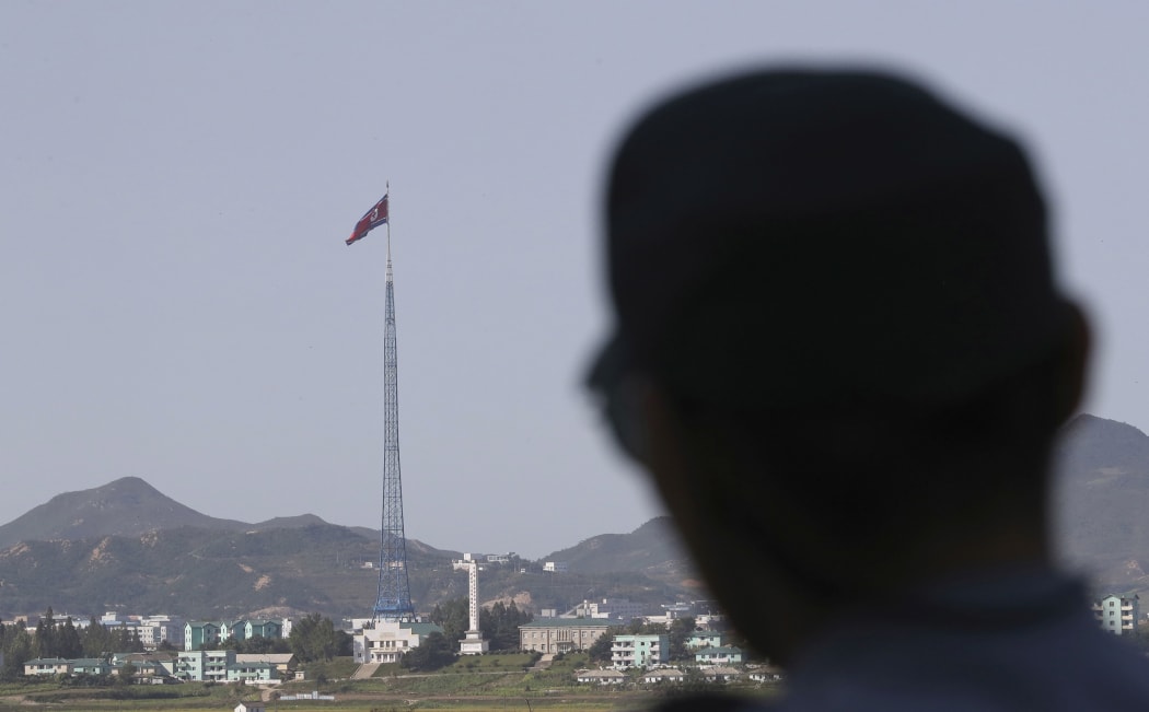 FILE - In this Sept. 28, 2017 file photo, A North Korean flag atop a 160-meter  tower in the North's Kijong-dong village as a South Korean soldier stands near the truce village of Panmunjom in the Demilitarized Zone which has separated the two Koreas since the Korean War, in Paju, South Korea.