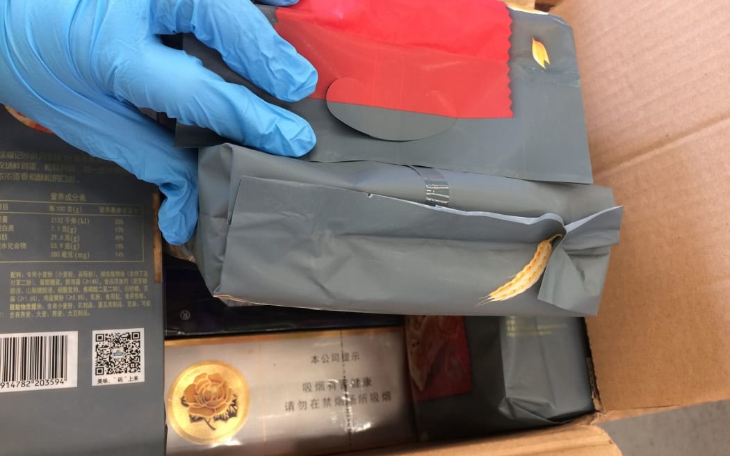 A closeup of cigarettes revealed in an opened box disguised as foodstuffs.