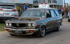 A old-style car with the engine viewable through the bonnet.