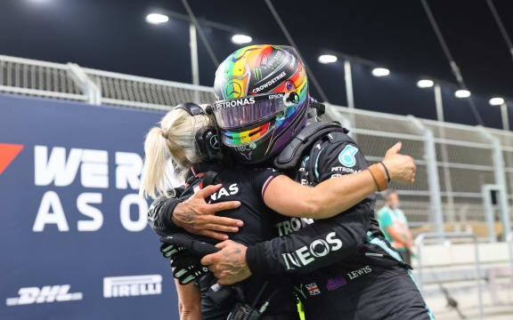 Mercedes' British driver Lewis Hamilton celebrates with a team members in the parc ferme after taking pole position in  the qualifying session of the Formula One Saudi Arabian Grand Prix at the Jeddah Corniche Circuit in Jeddah on December 4, 2021.