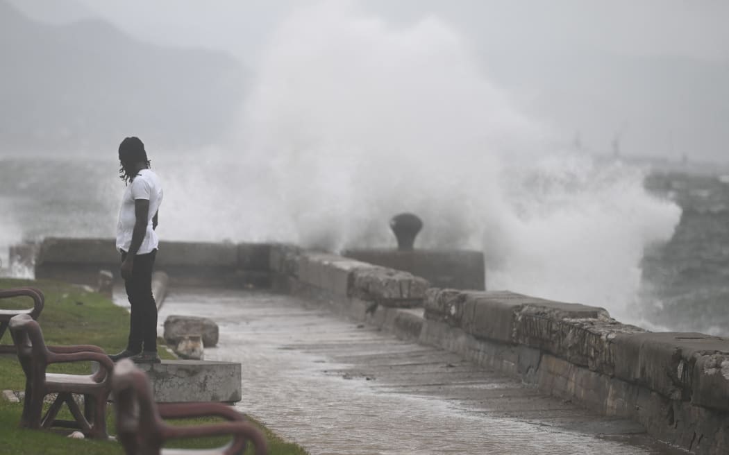 A man watches the waves crash into the walls at the Kingston Waterfront on October 27, 2025. Hurricane Melissa threatened Jamaica with potentially deadly rains after rapidly intensifying into a top-level Category 5 storm, as residents scrambled for shelter from what could be the island's most violent weather on record. Melissa has already been blamed for at least four deaths in Haiti and the Dominican Republic, and was set to unleash torrential rains on parts of Jamaica in a direct hit on the Caribbean island. (Photo by Ricardo Makyn / AFP)