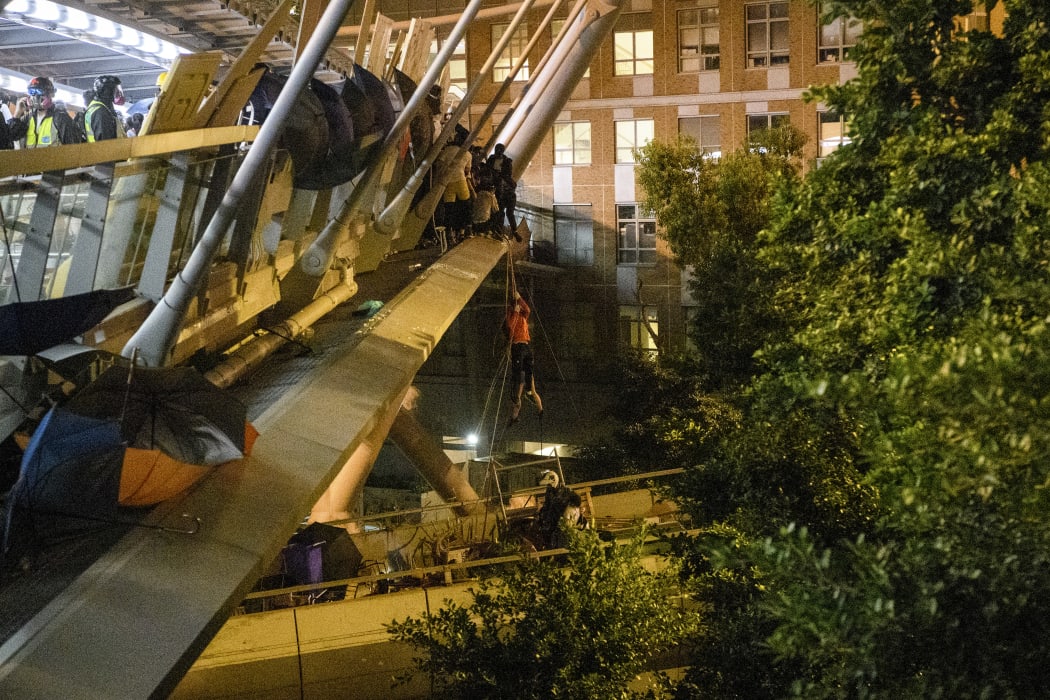 A protester lowers herself down a rope from a bridge to a highway, to escape from Hong Kong Polytechnic University campus and from police