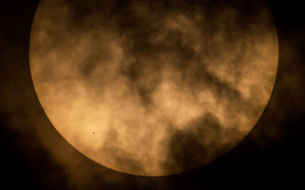 The planet Mercury is seen from NASA Headquarters in Washington DC, in silhouette, lower left, as it transits across the face of the sun.