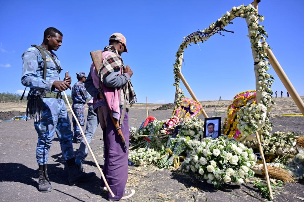 An ethiopian federal policeman and an Oromo tribesman look at a memorial to victims at the crash site of an Ethiopian airways operated Boeing 737 MAX aircraft on March 16, 2019  in Oromia region. -