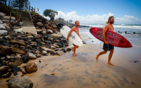 Two surfers negotiate massive beach erosion in the wake of cyclonic conditions at Byron Bay Main Beach on December 15, 2020, after wild weather lashed Australia's Northern New South Wales.