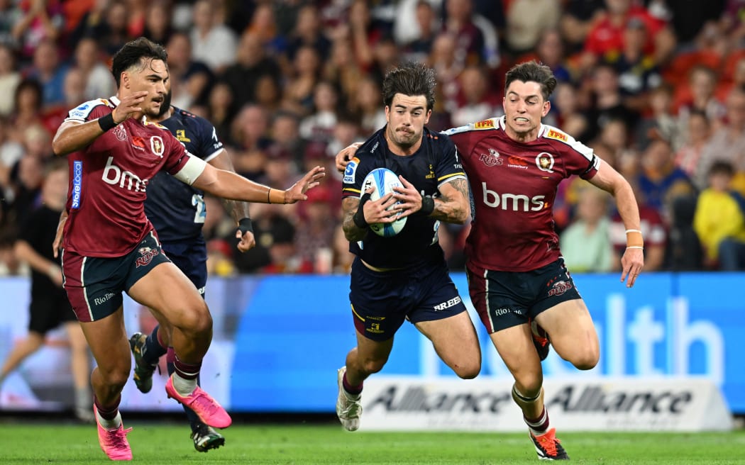 Connor Garden-Bachop (centre) of the Highlanders is tackled by Jordan Petaia (left) and Jock Campbell (right) of the Reds during the Super Rugby Pacific 2024.