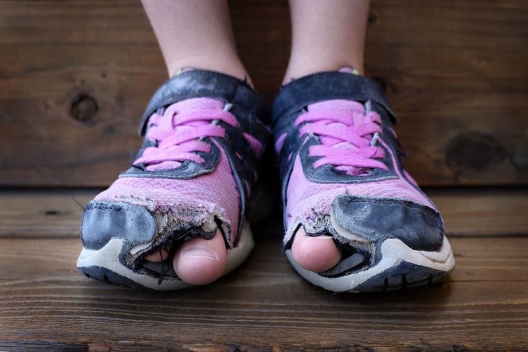 A child's feet in torn, old shoes.
