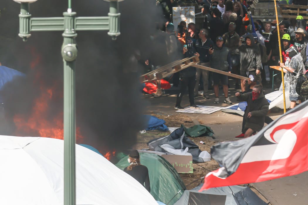 A first fire is lit and fuelled by protesters.