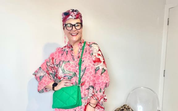Image of Auckland personal stylist Emma John, in a pink, red and white maxi dress, accessorised with a Kelly green cross body bag nad a multi-coloured headscarf worn as a turban.