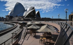 People walk near the Opera House in Sydney on June 26, 2021, after authorities locked down several central areas of Australia's largest city to contain an outbreak of the highly contagious Delta variant.