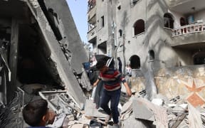 EDITORS NOTE: Graphic content / Children walk through the rubble of a destroyed building in a residential area in Deir al-Balah in the central Gaza Strip on April 7, 2025, following overnight Israeli airstrikes. The local civil defence agency said Israeli strikes killed at least 44 people in the Gaza Strip on April 6, one of them hitting a residential building in Deir al-Balah, killing several people, including women and children, according to witnesses. (Photo by Eyad BABA / AFP)