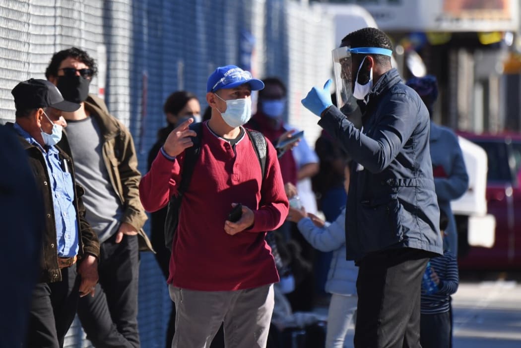 Covid-19 testing center staff speak to people waiting in line in the Brooklyn neighborhood of Borough Park on October 6, 2020 in New York City. (Photo by Angela Weiss / AFP)