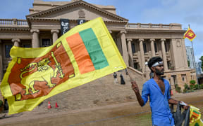 A man wears a headband with a slogan against interim Sri Lankan President Ranil Wickremesinghe as he waves the Sri Lankan national flag near the Presidential secretariat in Colombo on 17 July 2022.