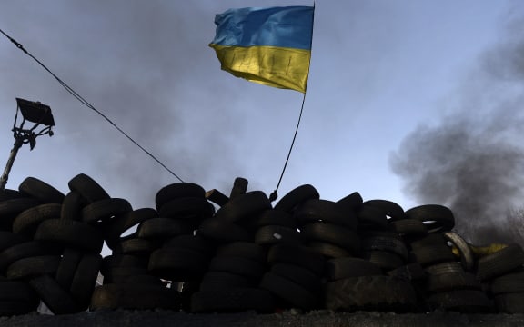 A Ukranian flag is waved behind a road block in Kiev on Monday.