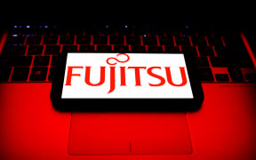 Fujitsu logo displayed on a phone screen and a laptop keyboard are seen in this illustration on October 30, 2021.