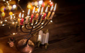 Concept of jewish holiday Hanukkah with menorah (traditional candelabra) and burning candles.