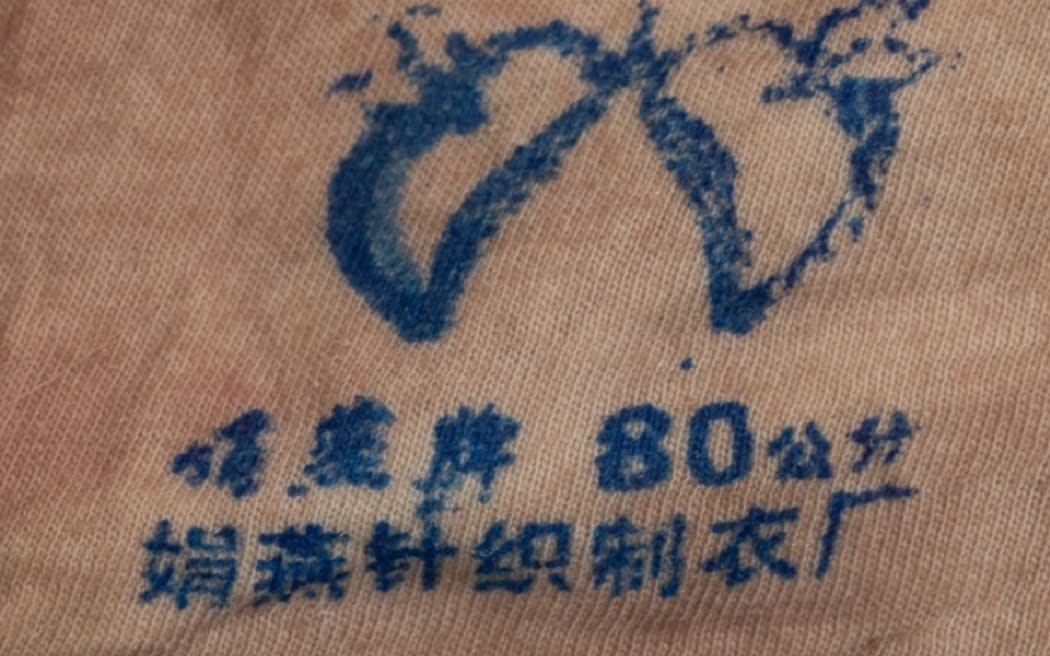 A brand's emblem on a light-coloured singlet found on the body of a woman found dead in Gulf Harbour on 12 March, 2024.