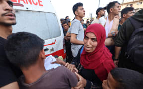 People react as Palestinian rescuers evacuate injured people in an ambulance after an Israeli drone reportedly opened fire on civilian gatherings near an aid distribution point not far from the so-called "Netzarim checkpoint", in the central Gaza Strip, on June 1, 2025, at Bureij camp, amid the war between Israel and the Palestinian Hamas militant movement. (Photo by Eyad BABA / AFP)