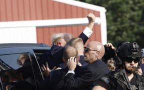 Republican presidential candidate former President Donald Trump pumps his fist as he is rushed into car after shots were fired at a campaign rally in Butler Pennsylvania, on 13 July, 2024.