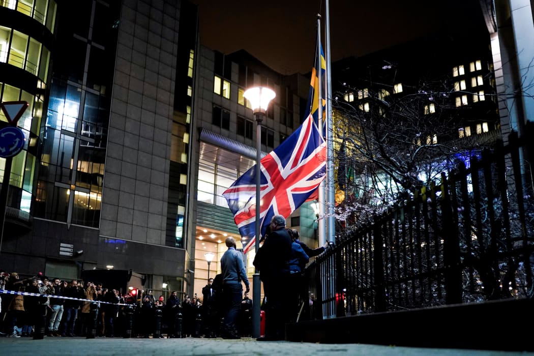 People take down the United Kingdom's flag from outside the European Union Parliament in Brussels.