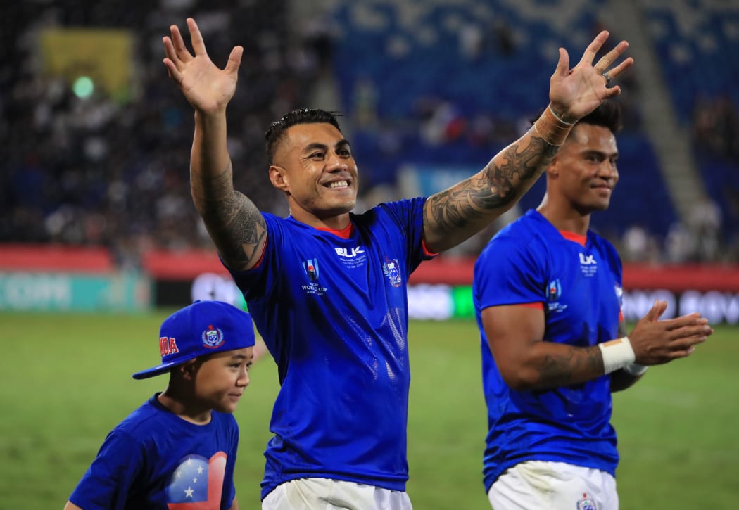 Tusi Pisi (c) waves to the crowd alongside his son Theron.