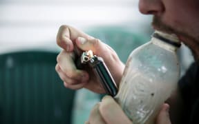 A male smoking using a homemade bong.