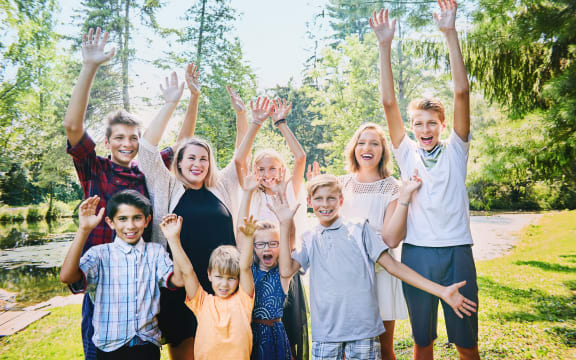 A photo of happy brothers and sisters  raising arms in the park