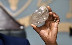 Botswana's President Mokgweetsi Masisi holds a large diamond discovered in Botswana at his office in Gaborone on August 22, 2024. The 2492 carat diamond was discovered in the Karowe mine in Botswana of Lucara Diamond Company. Botswana is one of the world's largest producers of diamonds, which constitute its main source of income, representing 30% of GDP and 80% of its exports. (Photo by Monirul BHUIYAN / AFP)