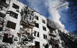 Firefighters work on a fire on a building after bombings on the eastern Ukraine town of Chuguiv on February 24, 2022.