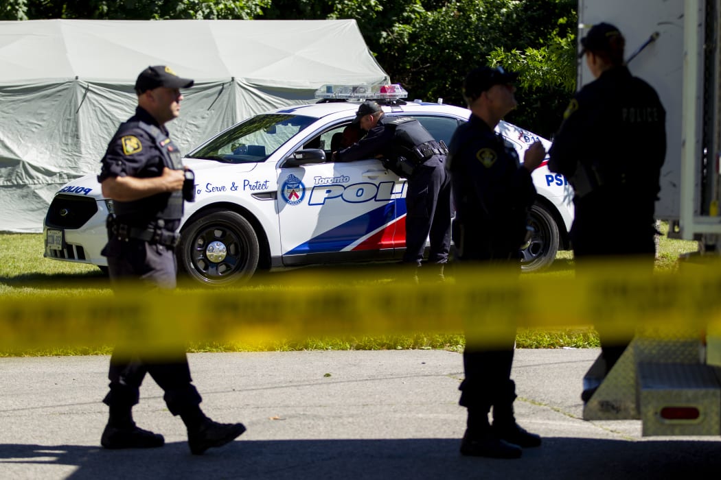 Members of the Ontario Provincial Police confer with colleagues after a third day of searching for human remains in a ravine behind a home on Mallory Crescent in Toronto, Ontario, July 6, 2018 in connection with the investigation of accused serial killer Bruce McArthur.