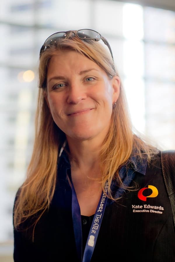 Kate Edwards is a smiling woman with long blonde hair and sunglasses on her head.