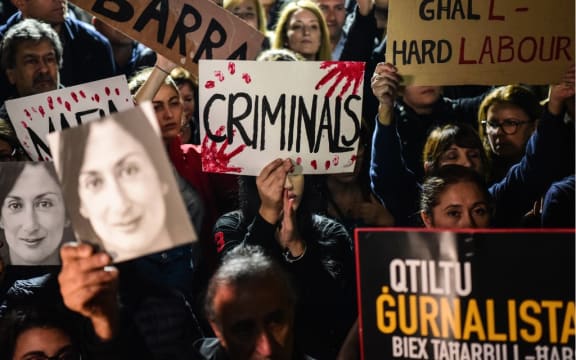 People holding placards and photos of killed journalist Daphne Caruana Galizia, stage a protest called by Galizia's family and civic movements, on November 29, 2019 outside the office of the prime minister in Valletta, Malta.