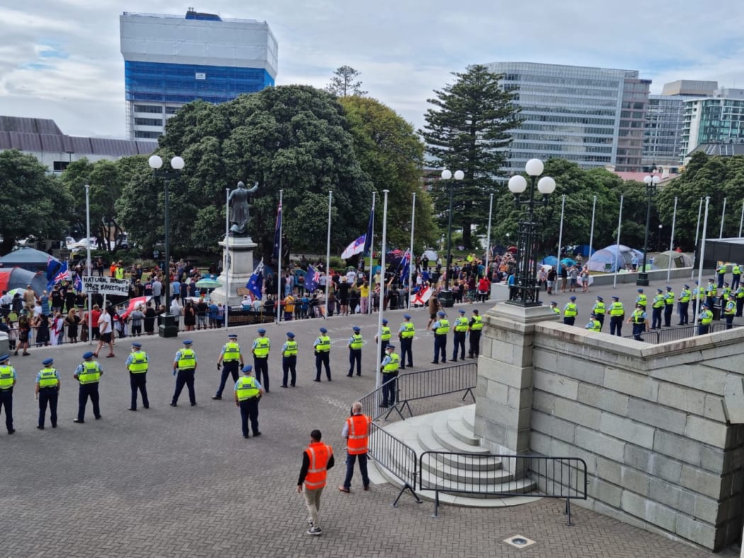 More than 50 police have formed a ring around the front of Parliament edging up to a line of protesters who had linked arms lining up in front of the cenotaph.