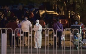 Residents stand next to a barrier inside at a residential area under lockdown to curb the spread of the Covid-19 coronavirus in Panjiayuan, Chaoyang district, in Beijing on April 27, 2022