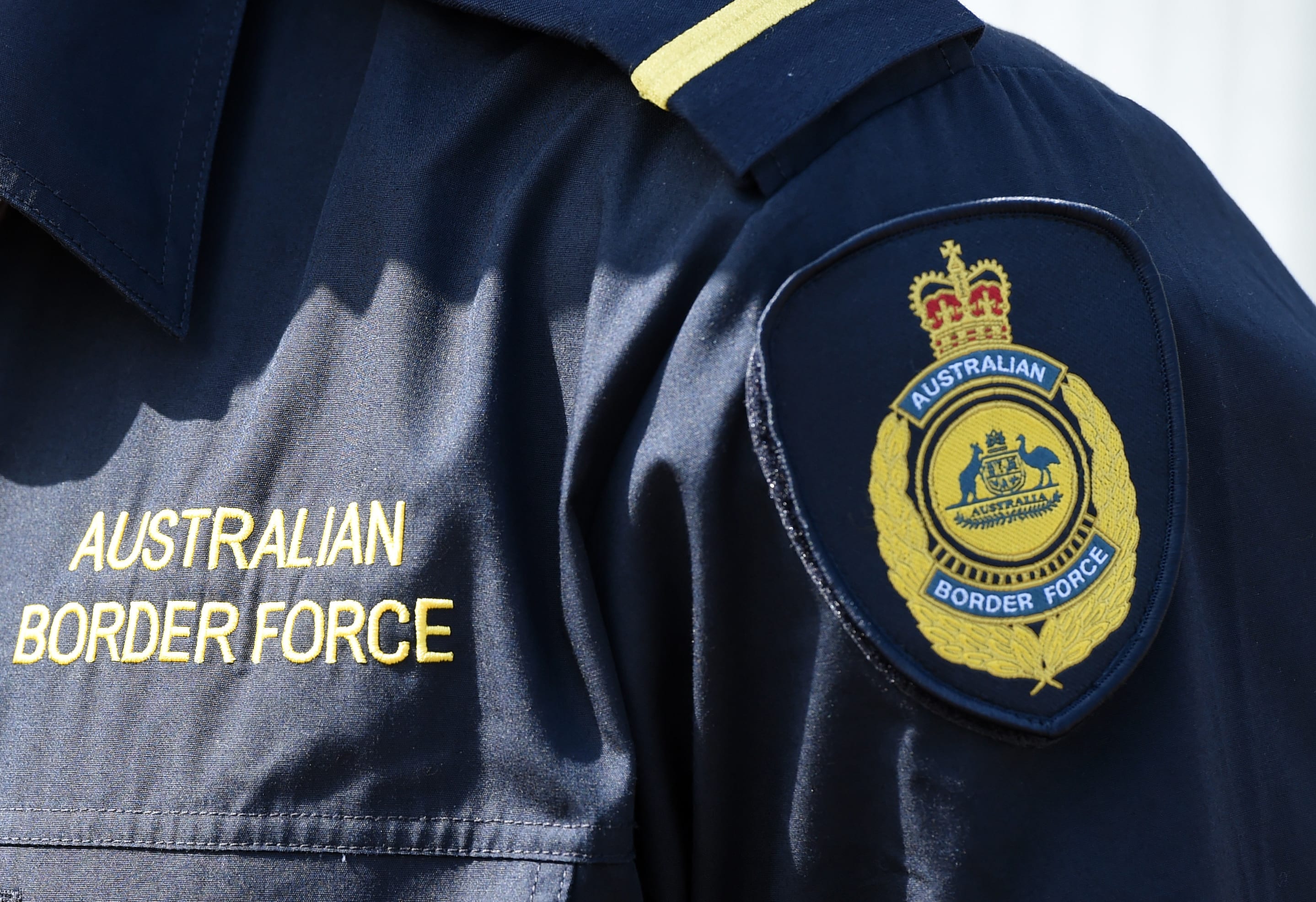 An Australian Border Force (ABF) badge can be seen on an officer's shirt.